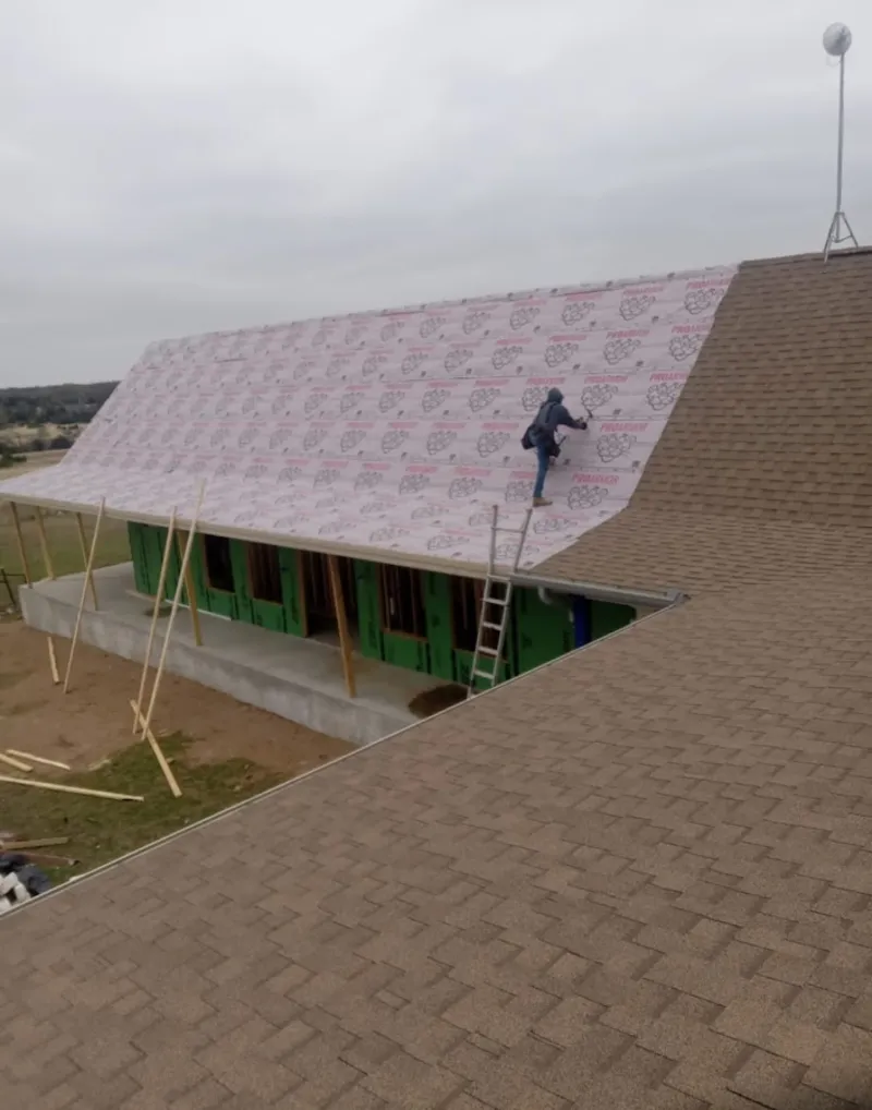 Worker preparing underlayment for a metal roof installation in North Brunswick